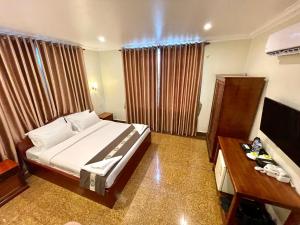 a bedroom with a bed and a desk and a television at You Mean Heng Guesthouse in Kampot