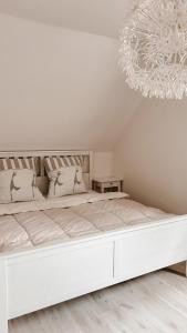 a white bedroom with a large bed with a chandelier at Modern wohnen, nahe Steinhuder Meer in Hagenburg