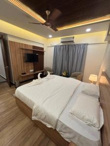 a bedroom with a large white bed and a television at Reva suites in Arsikere