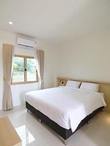 een slaapkamer met een wit bed en een raam bij เดอะริม รีสอร์ท The Rim Resort in Ban Muang