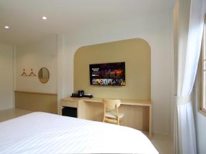 een slaapkamer met een bed en een bureau met een tv aan de muur bij เดอะริม รีสอร์ท The Rim Resort in Ban Muang