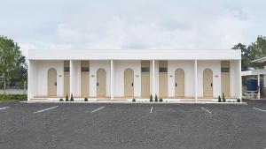 een wit gebouw met kolommen en een parkeerplaats bij เดอะริม รีสอร์ท The Rim Resort in Ban Muang