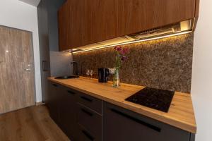 a kitchen counter with a sink and a vase of flowers at Sky Pool Escape Luxury Apartment in Druskininkai Center in Druskininkai