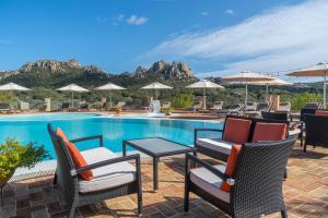 una piscina con sillas y sombrillas junto a una mesa en Felix Hotels - Country Resort Parco degli Ulivi, en Arzachena