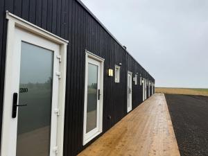 a black building with white doors and a wooden floor at The Hvítá Inn by Ourhotels in Bær