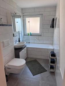 a bathroom with a toilet and a tub and a sink at Unger's Ferienwohnung in Isny im Allgäu