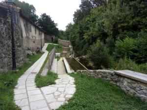 a stone path next to a river next to a building at Pension Dehesa in La Cavada