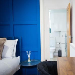 a blue bedroom with a bed and a table at Luxury Guesthouse by The Hive WA1 in Warrington