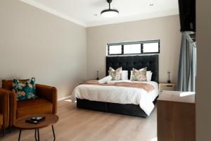 a bedroom with a large bed and a chair at Walton Cottages of Mill Park, Port Elizabeth in Port Elizabeth