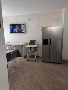 a kitchen with a refrigerator and a tv on the wall at Bariola Apartment in Caronno Pertusella