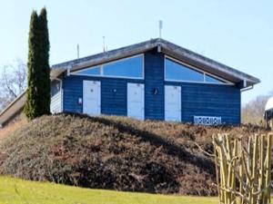 オーベンローにあるAabenraa Campingの丘の上にある白いドアが付いた青い建物