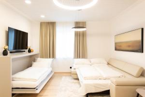 Una sala de estar con muebles blancos y un televisor de pantalla plana. en Frant Living - Graz Apartments, en Graz