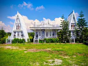 a white building with two towers on top of a field at Boat and House Resort Khao Kho in Khao Kho