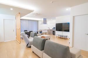 a living room with couches and a flat screen tv at Locanda katsuren 勝連荘 in Miyako Island