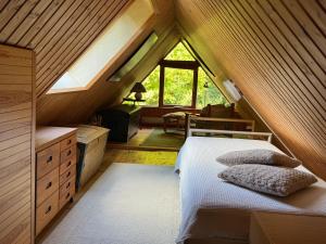 a attic bedroom with a bed and a window at Smedens Hus in Svarvaremåla