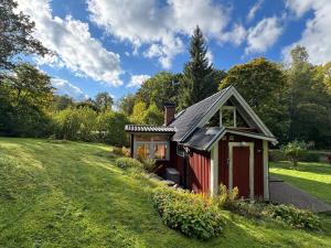 a small red house in a grassy field at Smedens Hus in Svarvaremåla