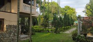 a house with a yard with trees and a building at Upavan Homestay in Lataguri