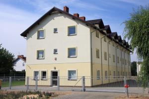 a large white house behind a fence at Leo Hostel in Poznań