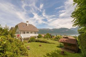 a house on a lawn with a view of the water at Villa Signature - Vue Panoramique 9p in Sévrier