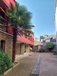 a palm tree in front of a red building at Le Rubis - hyper centre et proche plage in Dinard