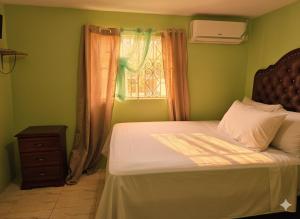 a bed in a green room with a window at Private Villa Paradise - Pool & Mountain Views in Top Hill