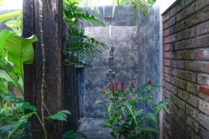 a shower in a garden with red flowers at Dhyana Beach Villa in Ambalangoda