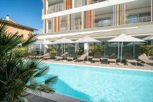 a swimming pool with chairs and umbrellas next to a building at Felix Hotels - Hotel Felix Olbia in Olbia