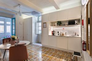 a kitchen with white cabinets and a table and a table and chairs at Valletta Letcom Studio in Valletta +37 photos