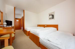 a bedroom with two beds and a desk and a computer at Hotel SOREA HUTNÍK in Vysoké Tatry +34 photos