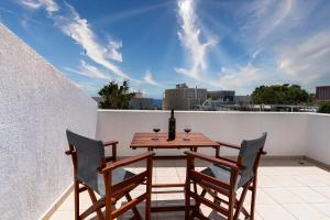 a table with two chairs and a bottle of wine on a balcony at Elea Sun Hotel in Kamari
