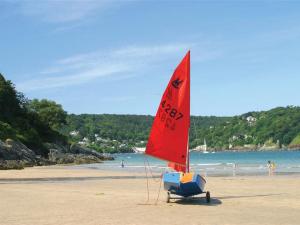 Un velero rojo en una playa con gente en la playa. en St Leonards, en Salcombe