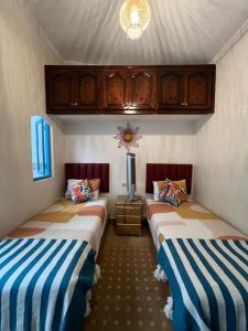 マラケシュにあるRiad Noureddineのベッド2台 木製キャビネット付きの部屋