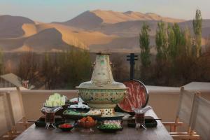 a table with a vase on a table with food at DunHuang FengMingSha Hotel in Dunhuang