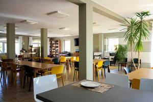 a dining room with tables and yellow chairs at Agriostello delle Langhe in Farigliano