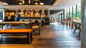 a restaurant with wooden tables and chairs and windows at Novotel Suites Reims Centre in Reims +17 photos