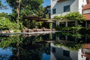 a pool with chairs and umbrellas next to a building at Le Clos Du Fil in Ninh Binh