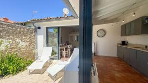 a kitchen and dining room with white chairs in a house at Dans le centre village de Sainte Marie de Ré, charmante location entièrement rénovée in Sainte-Marie-de-Ré