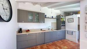 a kitchen with gray cabinets and a large clock on the wall at Dans le centre village de Sainte Marie de Ré, charmante location entièrement rénovée in Sainte-Marie-de-Ré +4 photos