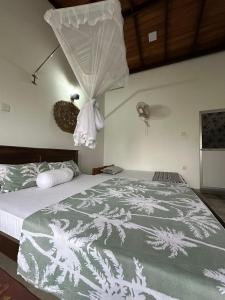a bedroom with a bed with a comforter on it at Royal Resort in Weligama