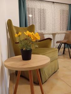 Una mesa con un jarrón de flores amarillas sobre una silla. en Navigo house, en Vrachati
