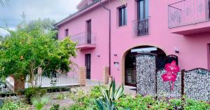a pink house with a gate and flowers in front at Residenza Locci - Rooms & Apartments in Teulada