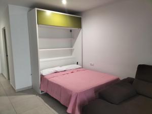 a small bedroom with a pink bed and a couch at Bungalow Médano in El Médano