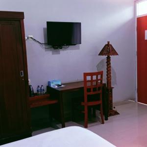 een slaapkamer met een bureau met een stoel en een televisie bij Hotel Inayah Syariah in Kumprung