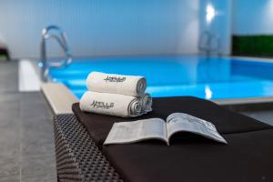 a pile of towels and a book next to a swimming pool at Impuls hotel in Vidin