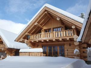 a log cabin with snow on the roof at Almzauber Chalets - Haus Enzian inkl Infrarotliegen in Hochrindl