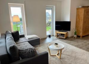 a living room with a couch and a tv at Ferienwohnung Im Laubgarten in Öhningen