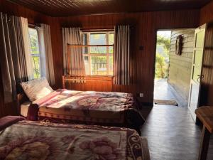 a bedroom with two beds and a window and a door at CRAB and STAY in Nuwara Eliya