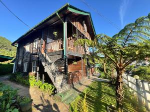 a wooden house with a balcony and a tree at CRAB and STAY in Nuwara Eliya