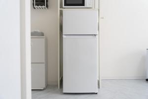 een witte koelkast met een magnetron erop bij Maison de Grue 601 in Sapporo