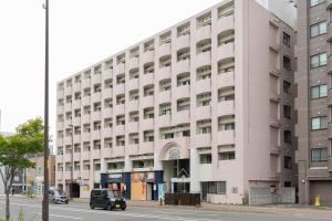een roze gebouw aan de kant van een straat bij Maison de Grue 601 in Sapporo